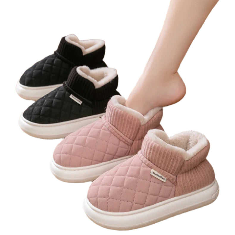 Pair of black and pink quilted winter slippers on a wooden floor.