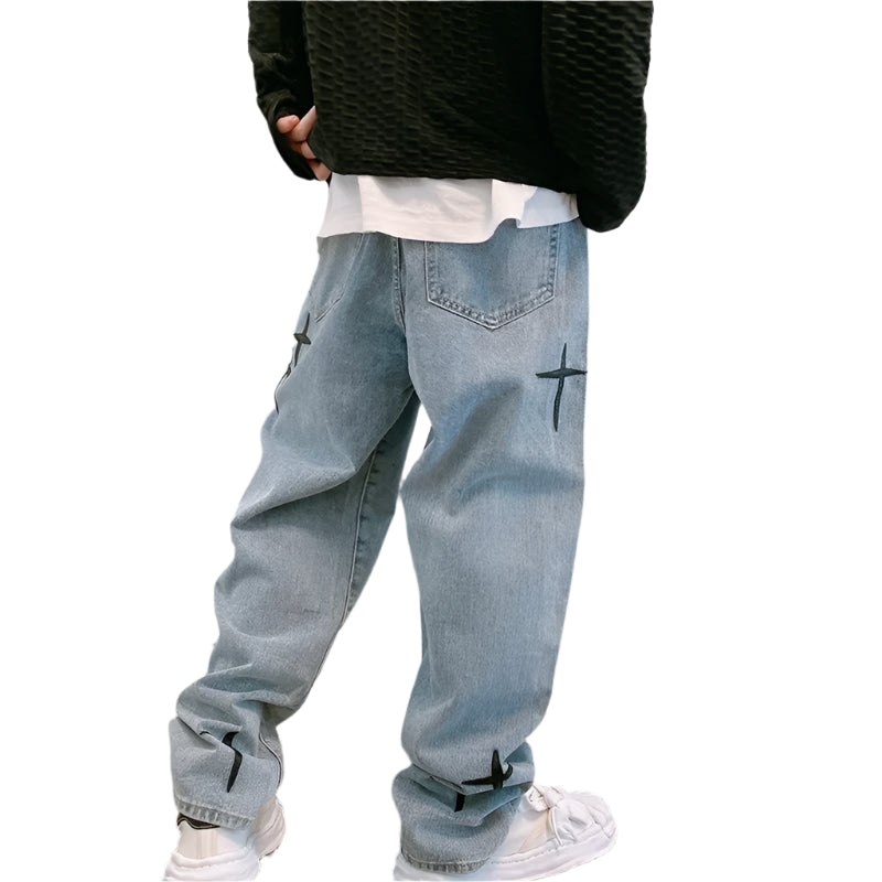 Person wearing light blue jeans with black star designs against a plain wall.
