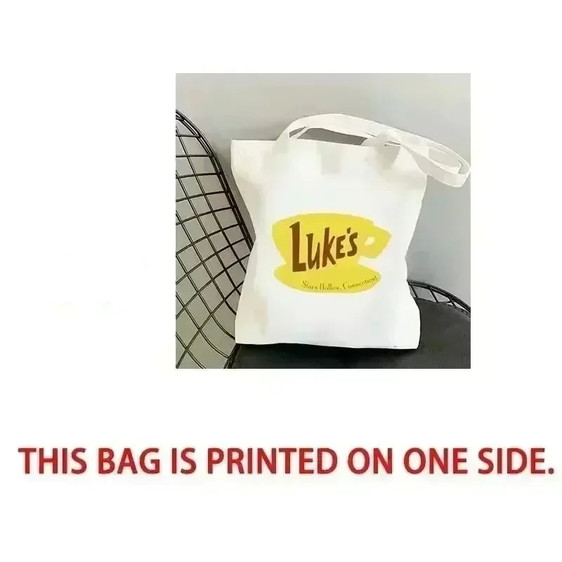 White tote bag with yellow logo on a black chair, labeled 'Front'.