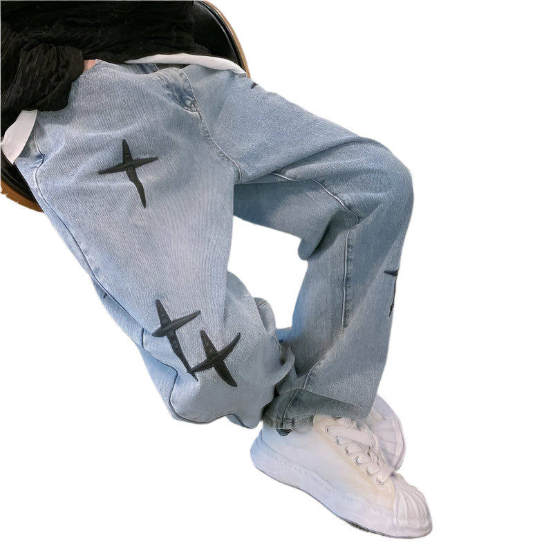 Light blue jeans with black star designs worn by a person sitting on a chair.