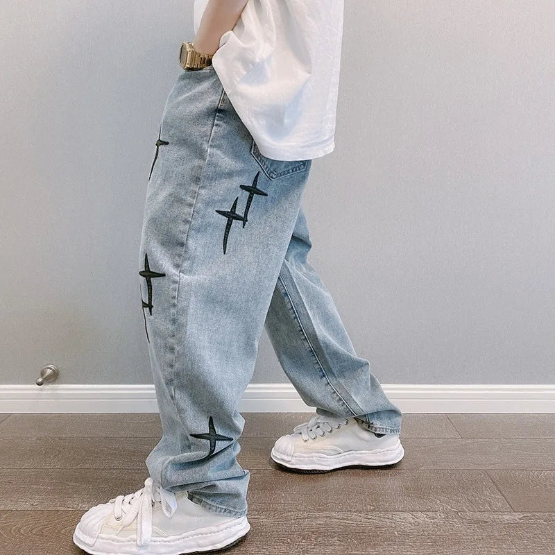 Light blue jeans with black patterns worn by a person indoors.