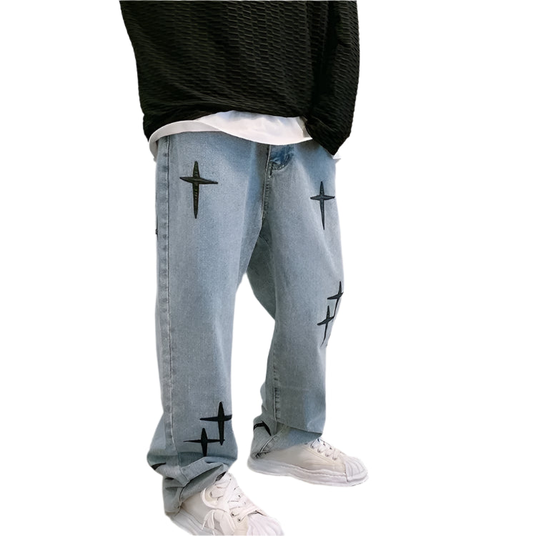 Person wearing light blue jeans with black star designs and a black top against a plain background