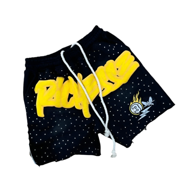 Black shorts with yellow text and white drawstring, paired with yellow sneakers on a gray surface.