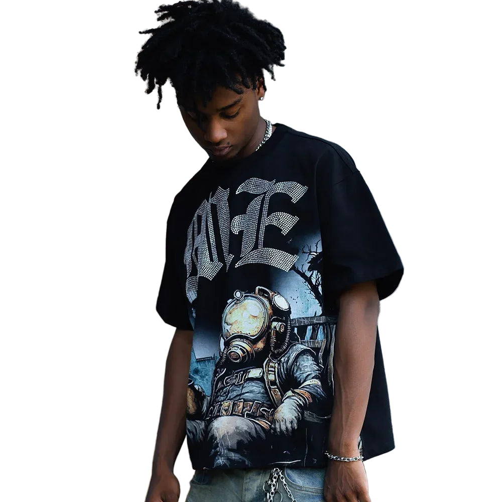 Person wearing a black graphic t-shirt with a detailed design against a gray wall.
