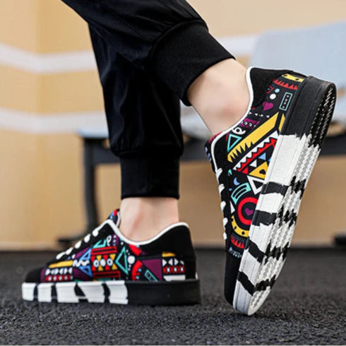 Colorful slip-on shoes with geometric patterns worn by a person on a blurred background.