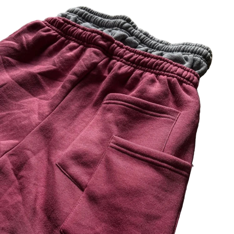 Maroon sweatpants with gray cuffs on a brown surface