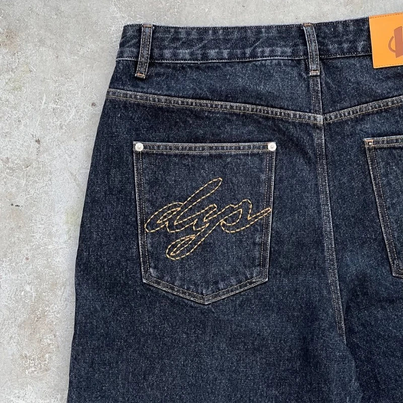 Dark blue denim jeans with a brand logo on the back pocket against a concrete floor background