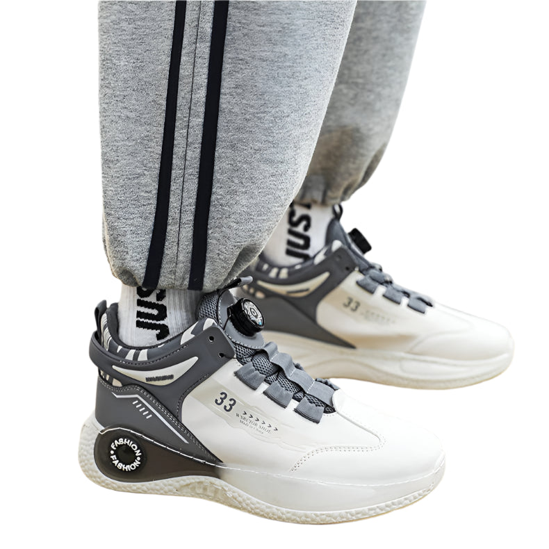 White and gray sneakers with '33' branding worn by a person on a yellow mat.