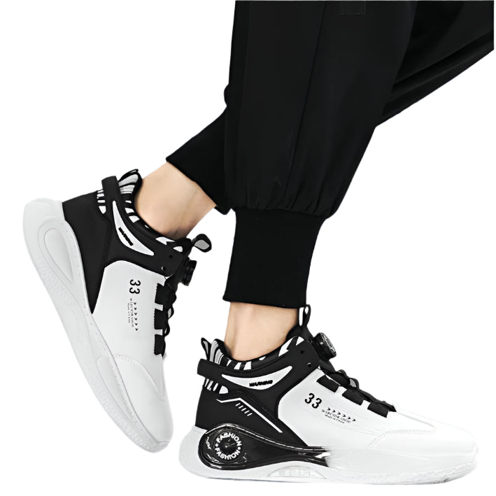 Black and white sneakers worn with black pants on a gray background