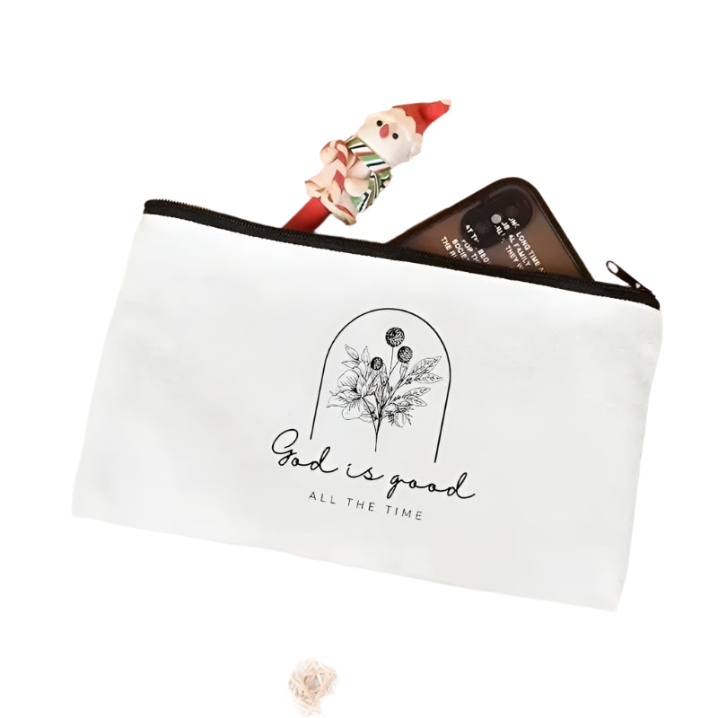 White pouch with 'God is good all the time' text and floral design on a pink surface.