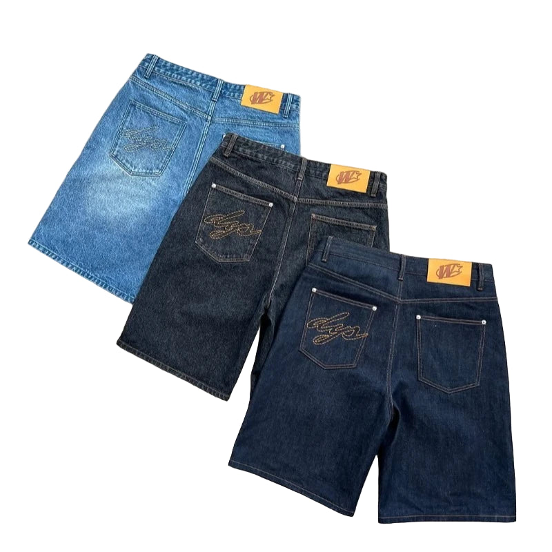 Three pairs of jeans in blue and black on a concrete surface with visible brand labels.