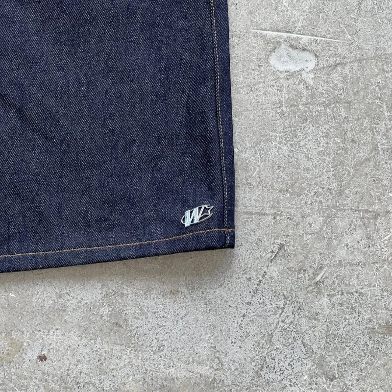 Close-up of a blue denim fabric corner with a logo on a concrete surface