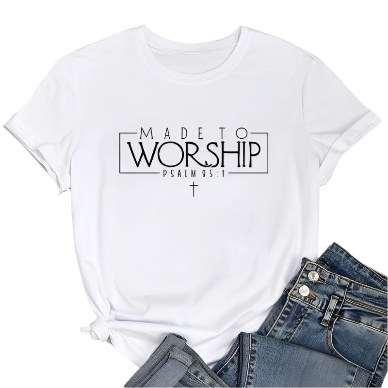 White t-shirt with 'Made to Worship' text on a wooden surface with jeans and sneakers.