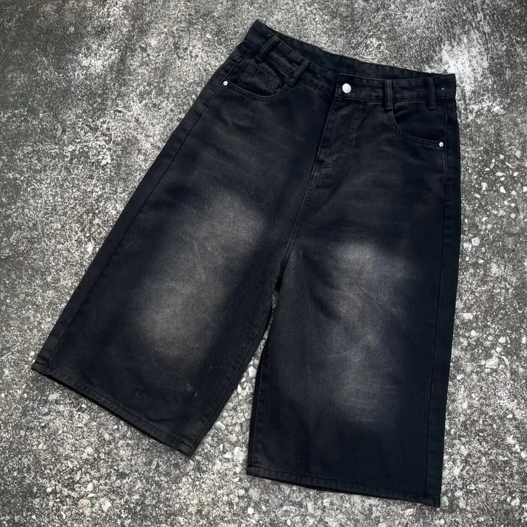 Black denim shorts on a textured gray surface