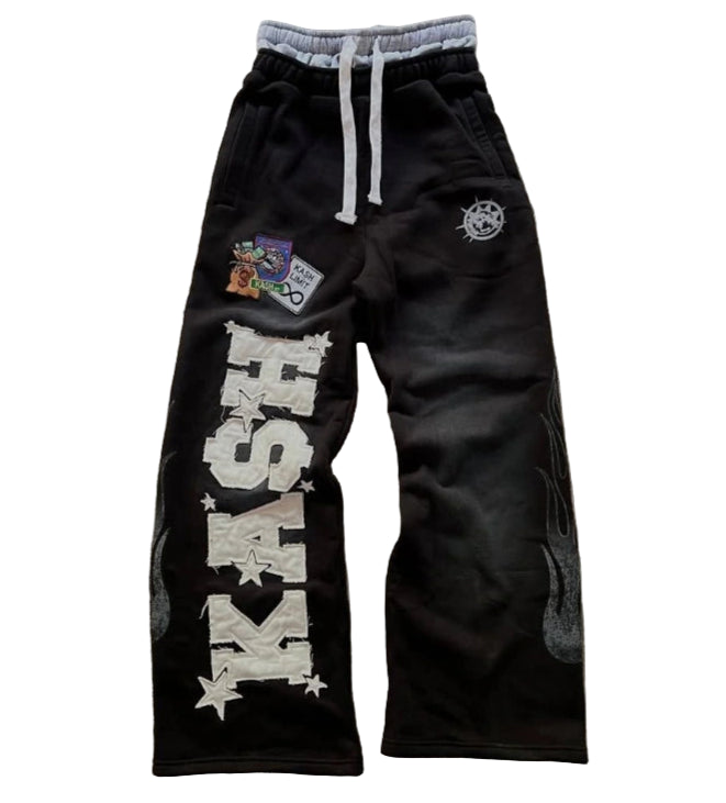 Black pants with 'KASH' text and patches on a textured surface