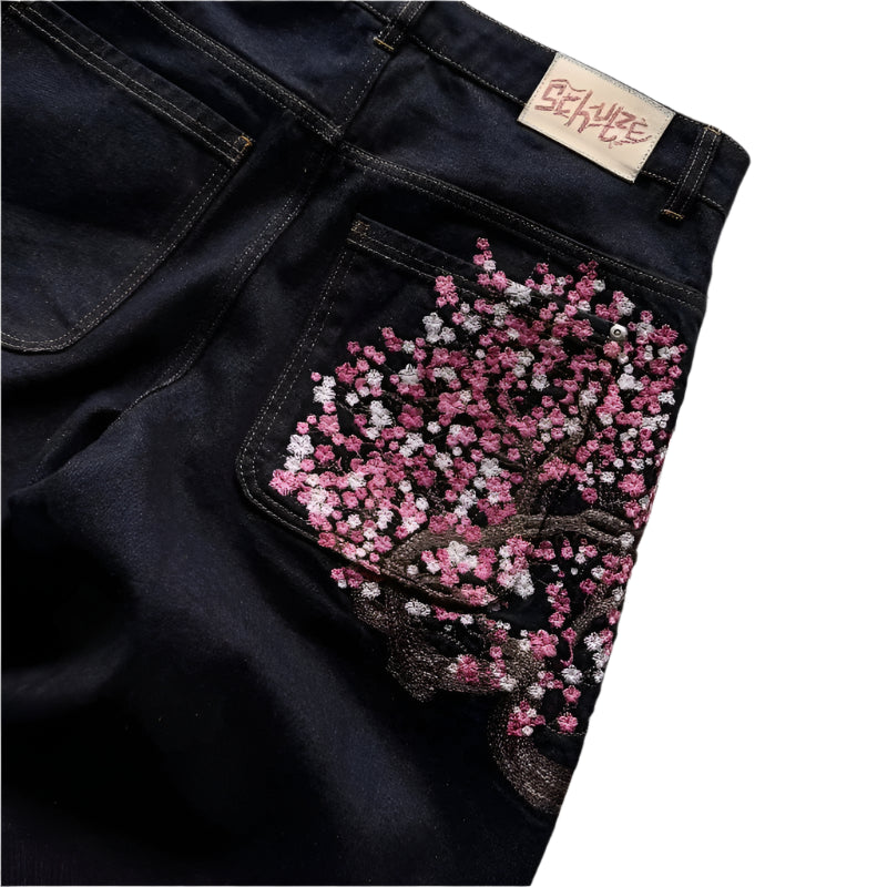 Dark blue jeans with a floral embroidered pocket on a concrete surface