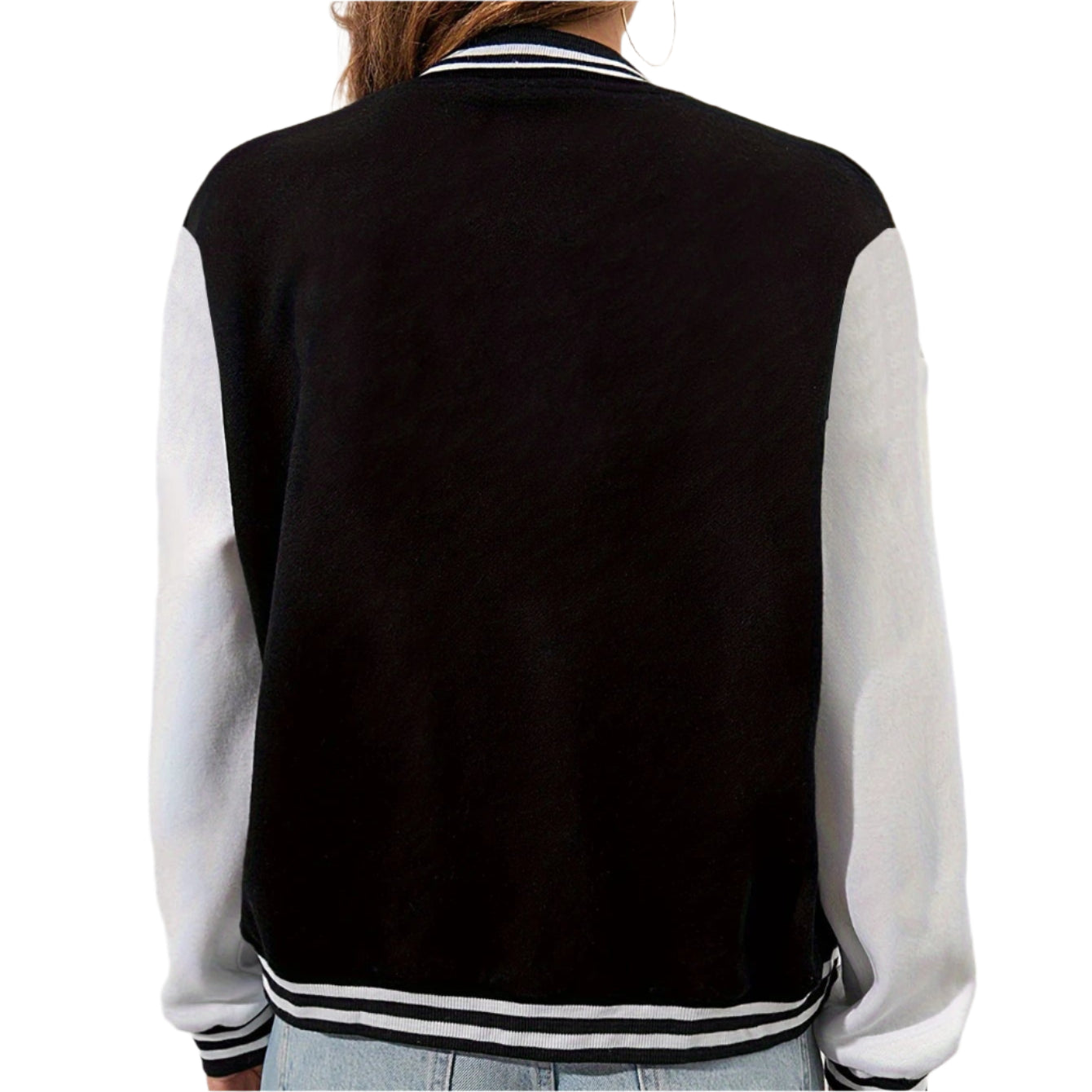 Person wearing a black and white varsity jacket with light blue jeans on a plain background