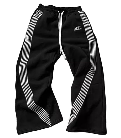 Black track pants with white stripes on a wooden floor
