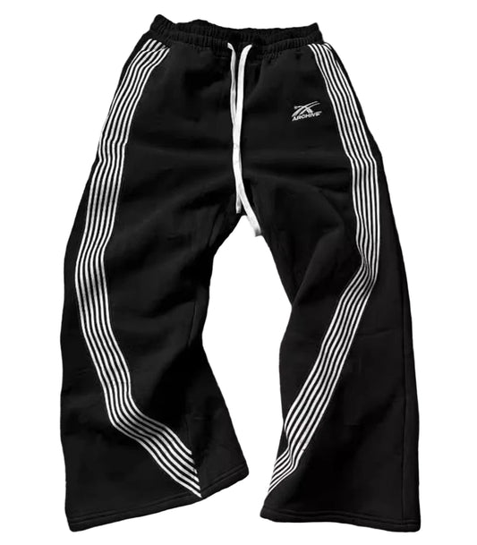 Black track pants with white stripes on a wooden floor