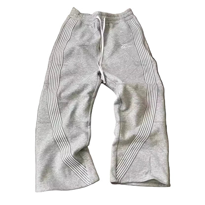 Gray sweatpants with white stripes on a wooden floor