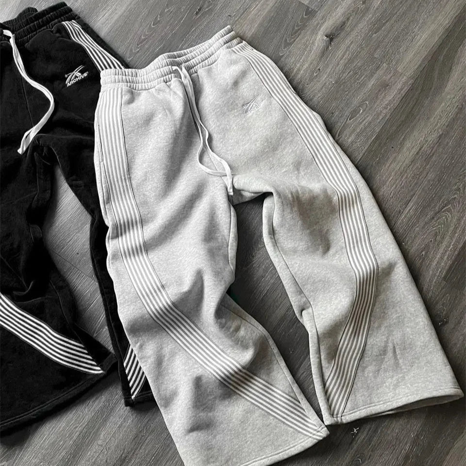 Gray sweatpants with white stripes on a wooden floor