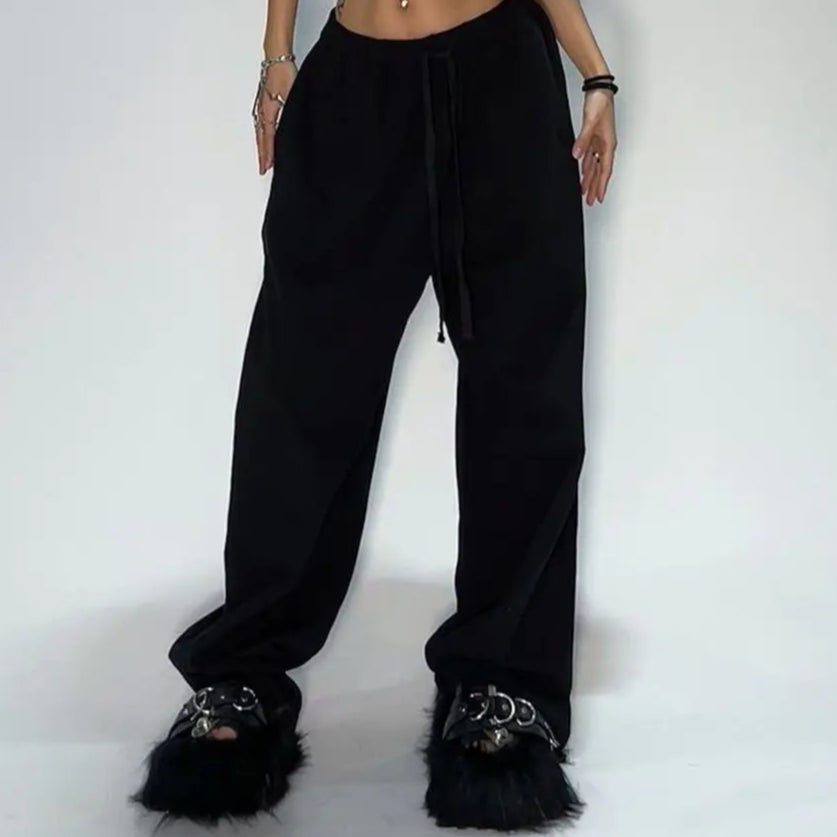 Person wearing a black outfit with fur-lined shoes on a white background