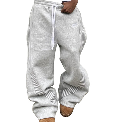 Person wearing gray sweatpants standing against a gray wall.