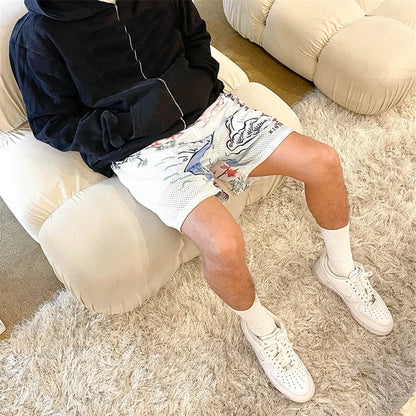 Person wearing a dark hoodie, patterned shorts, and white sneakers sitting on a fluffy chair.