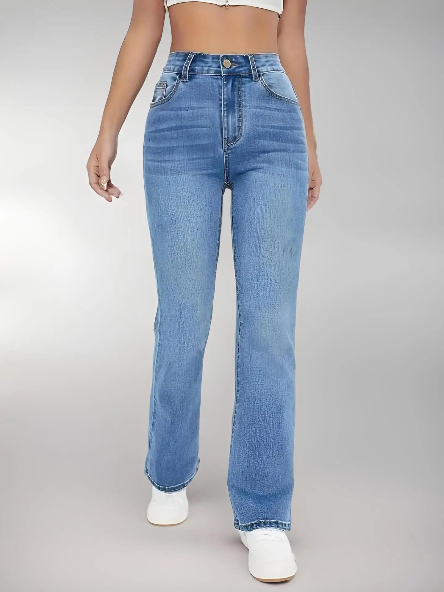 Person wearing blue jeans on a plain background