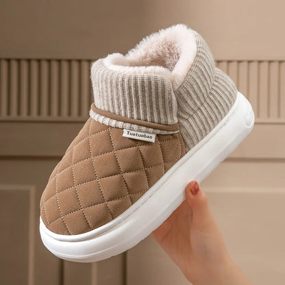 Brown quilted slipper with white sole held by a hand against a neutral background