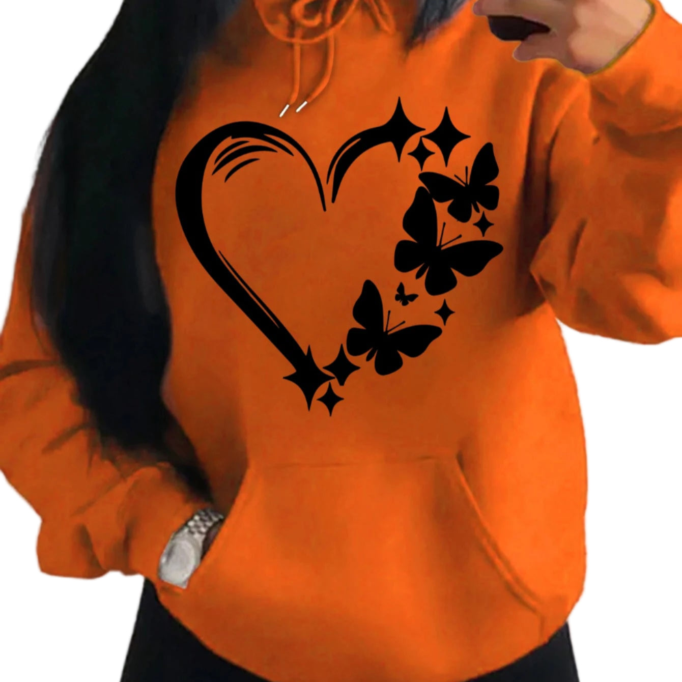 Orange hoodie with black heart and butterfly design worn by a person.