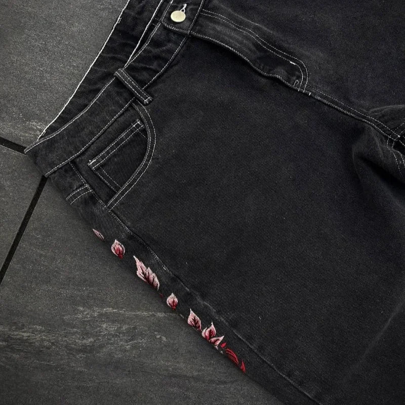 Black denim jeans with floral embroidery on a dark surface