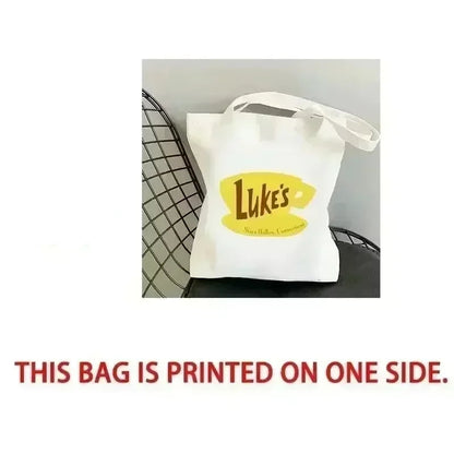 White tote bag with yellow logo on a black chair, labeled 'Front'.