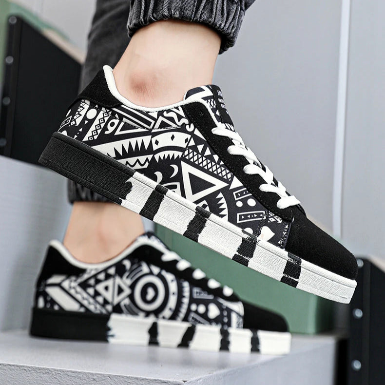 Black and white patterned sneakers worn with gray pants on a neutral background