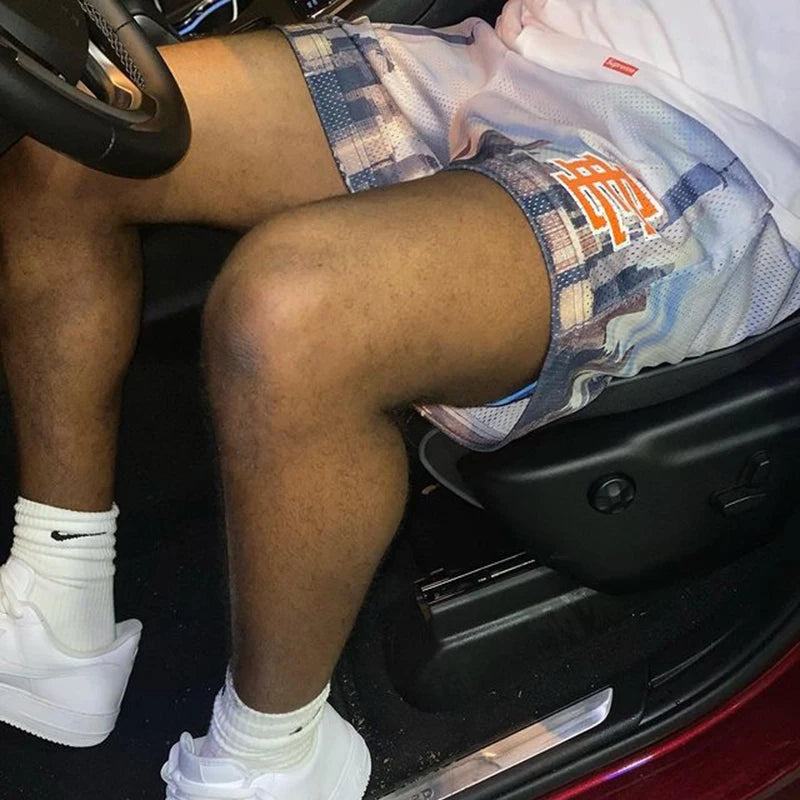Person sitting inside a car wearing patterned shorts and white sneakers.
