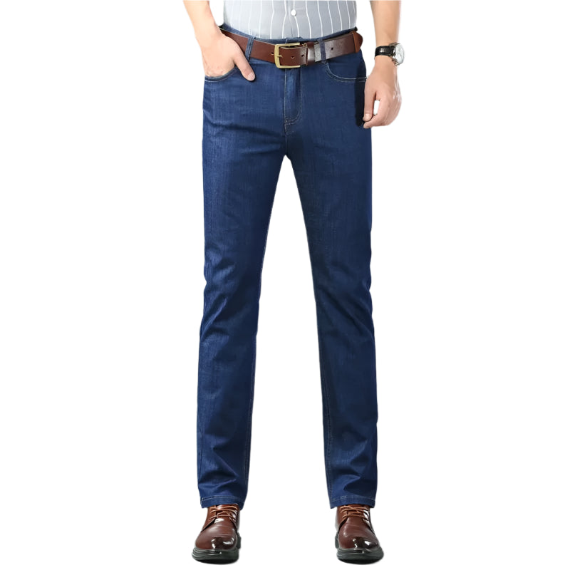 Person wearing blue jeans with a brown belt and shoes on a gray background