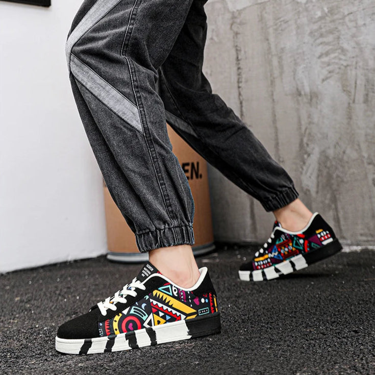Person holding a skateboard with 'SKATE' text, wearing colorful sneakers and black pants.