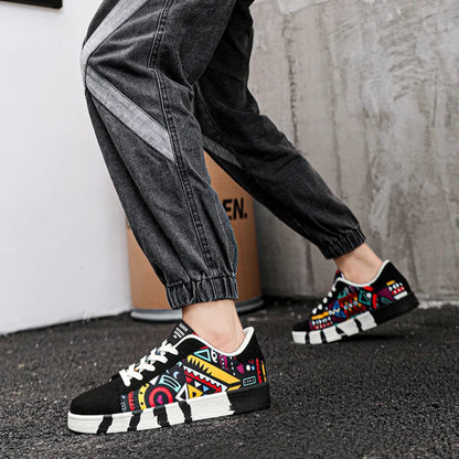 Person holding a skateboard with 'SKATE' text, wearing colorful sneakers and black pants.
