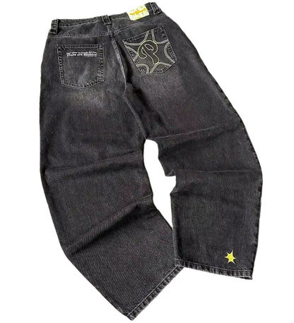 Black denim jeans with decorative stitching on a gray textured background