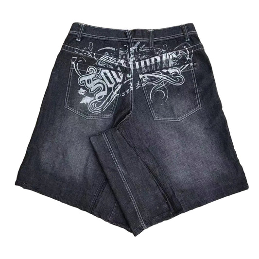Black jeans with white embroidery on a concrete surface