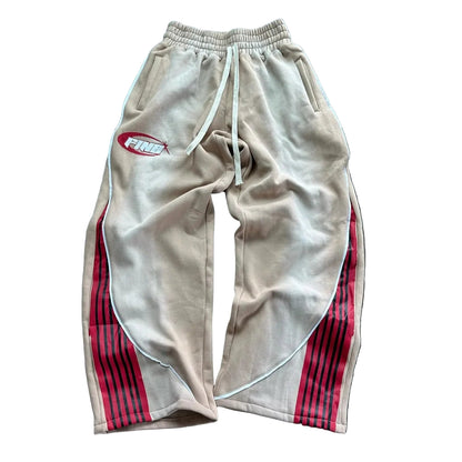 Beige sweatpants with red stripes and a logo on a wooden floor