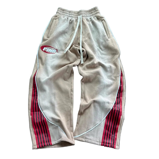 Beige sweatpants with red stripes and a logo on a wooden floor