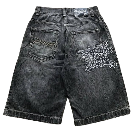 Black denim shorts with a decorative logo on a textured surface