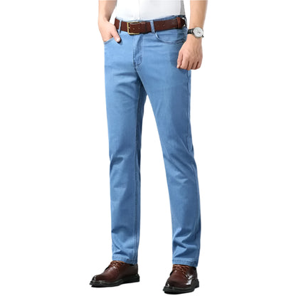 Person wearing light blue jeans with a brown belt and shoes on a gray background
