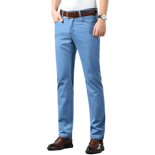 Person wearing light blue jeans with a brown belt and shoes on a gray background