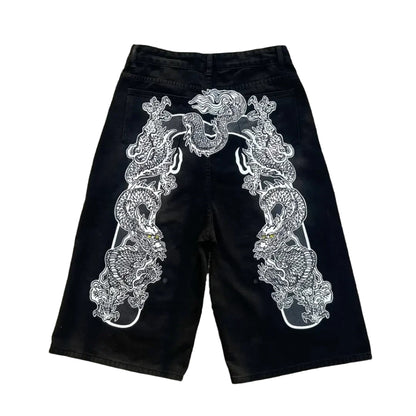 Black shorts with white embroidery on a concrete surface