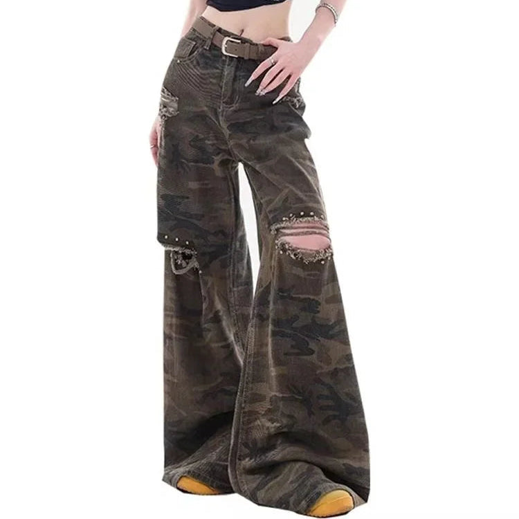 Person wearing a black t-shirt and camouflage pants with studded details on a white background