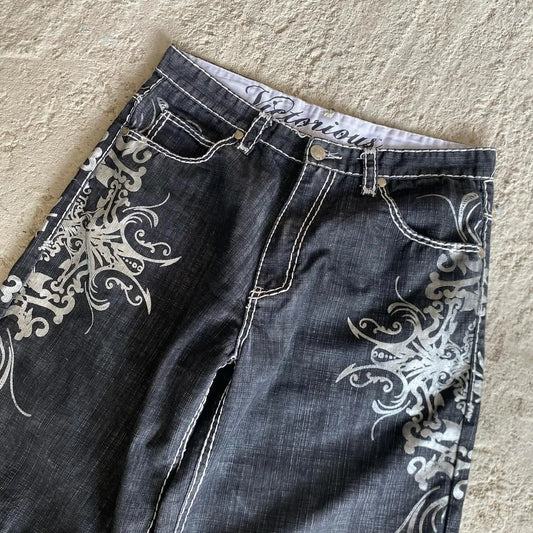 Black jeans with white floral patterns on a beige surface