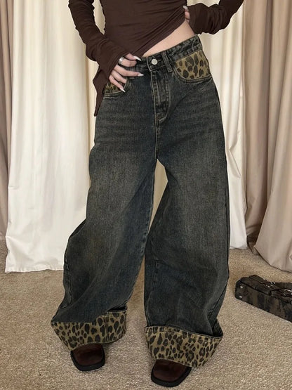 Person wearing wide-leg jeans with leopard print cuffs in front of beige curtains.