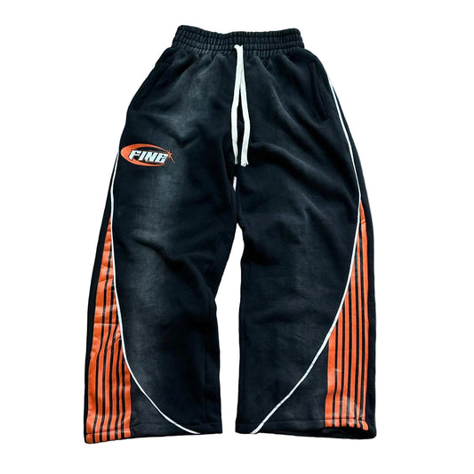 Black track pants with orange and white accents on a wooden floor